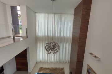 Cortina translúcida em sala com pé-direito duplo: a automação permite controlar a entrada de luz com um comando.